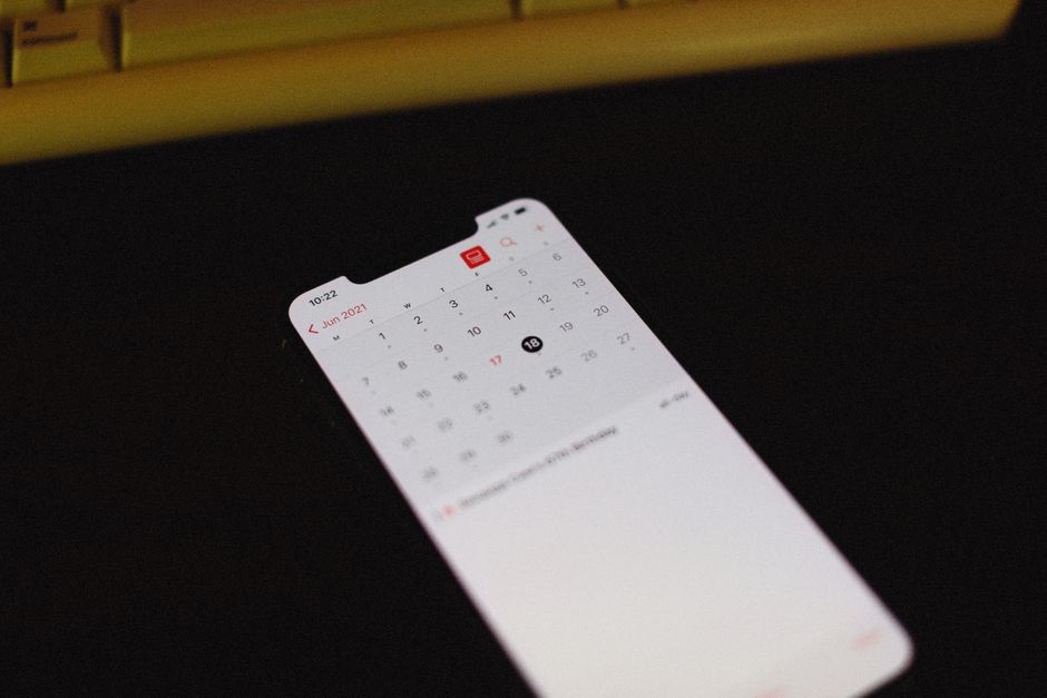 暗い机の上に置かれたカレンダーアプリを表示したスマートフォン